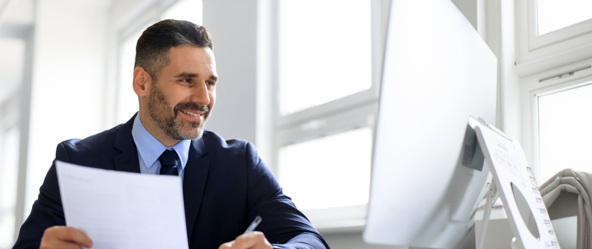 businessman working with computer and documents in office, manager in suit sitting at desk, checking company financial reports 