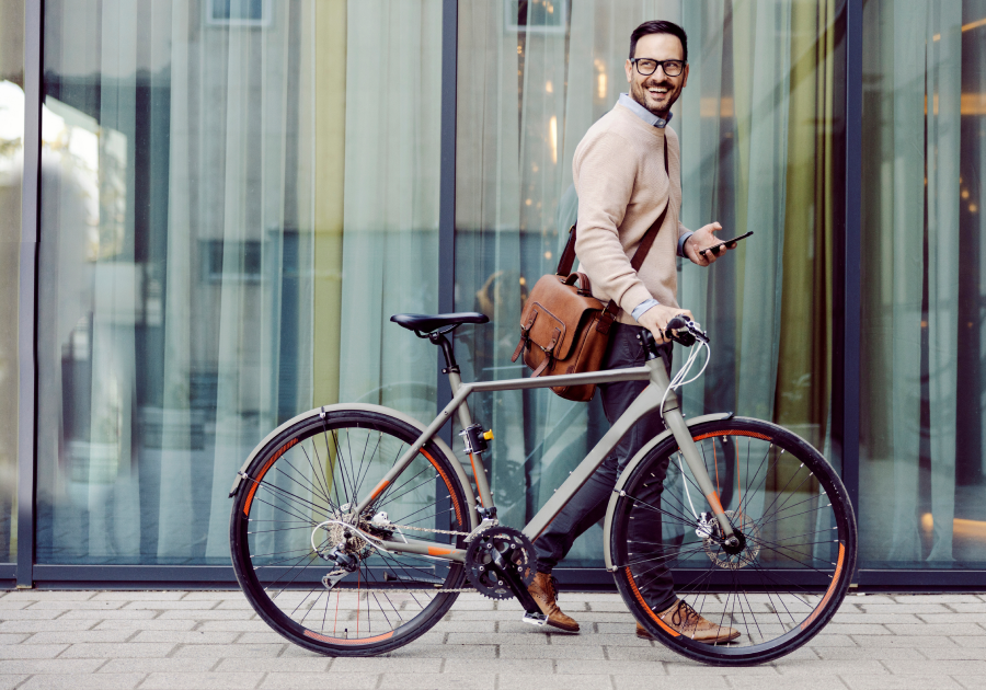 An urban man pushing bicycle and using phone while passing by window