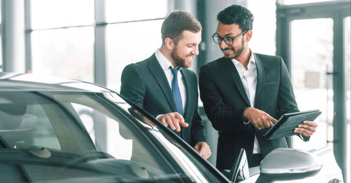 Two men looking at data on tablet in car shop