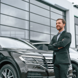 Man standing in front of car at car dealership