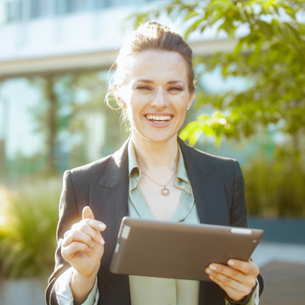 smiling woman looking at ipad in green surroundings