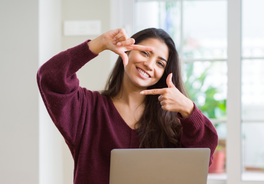 Young woman using computer laptop smiling making frame with hands and fingers with happy face.