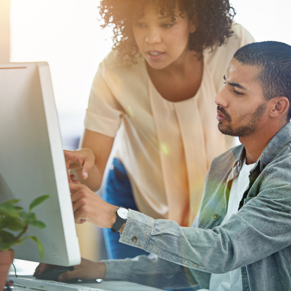 Man and woman sitting by a computer. Woman pointing to the screen-1